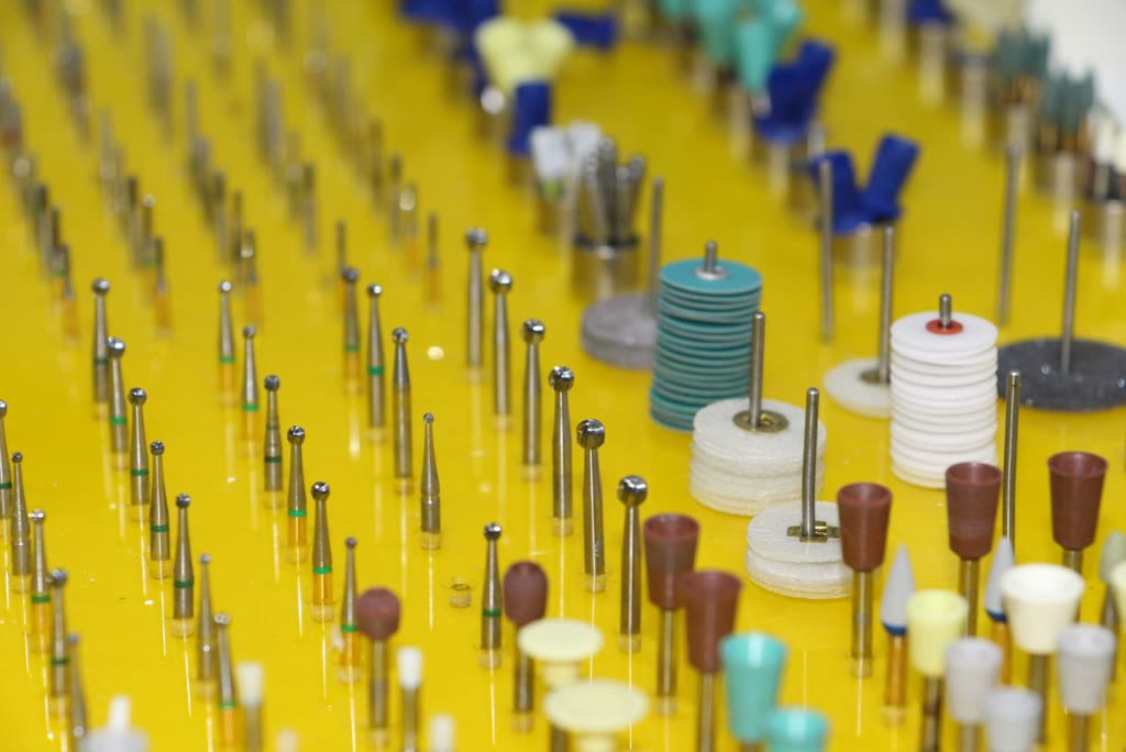Rows of polished dental burs and instruments arranged on a tray