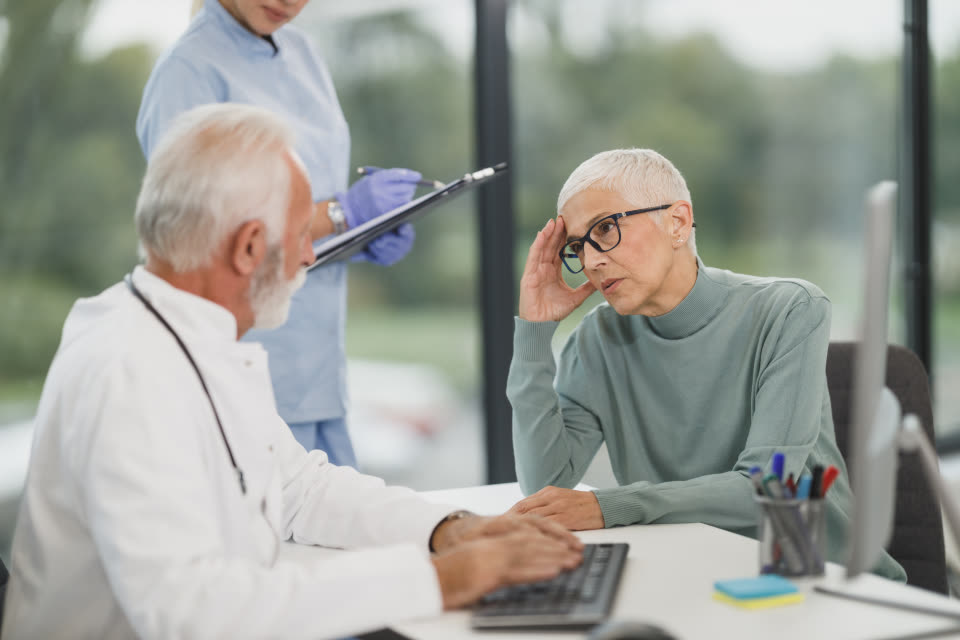 A dentist talking through results with a patient at a bright desk