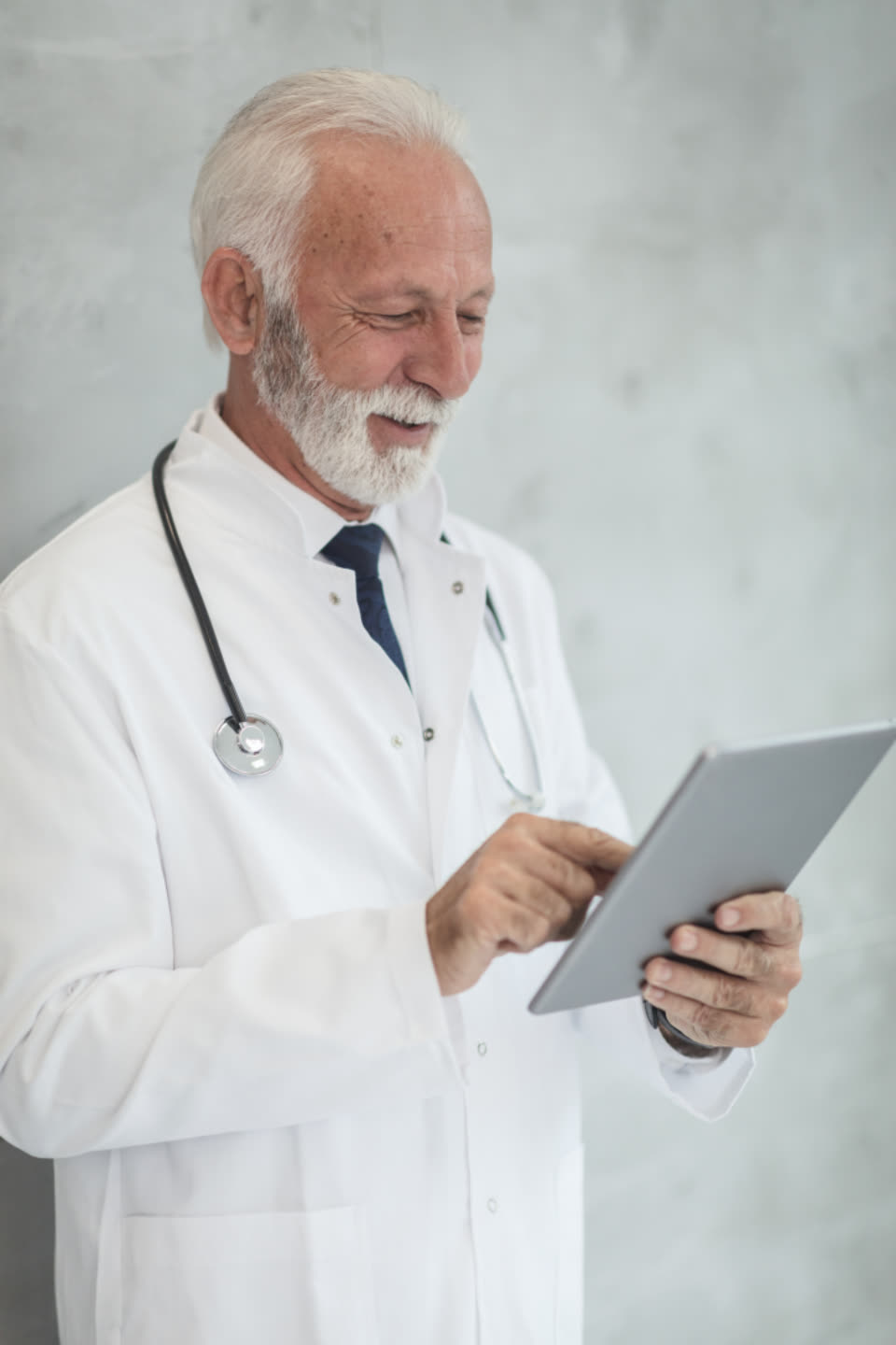 Dr. Henrik Lindqvist, a grey-bearded dentist in a white coat looking at a tablet